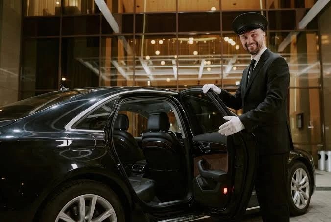 Chauffeur opening sedan door outside